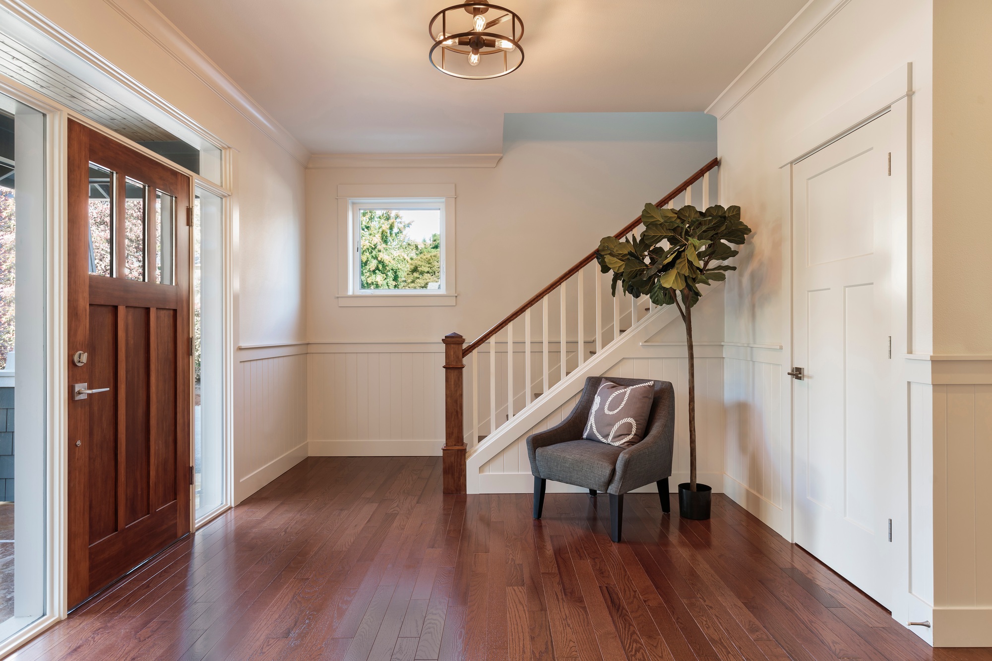 Cozy armchair next to a potted tree in a welcoming house entryway, with soft lighting and a minimalist décor style