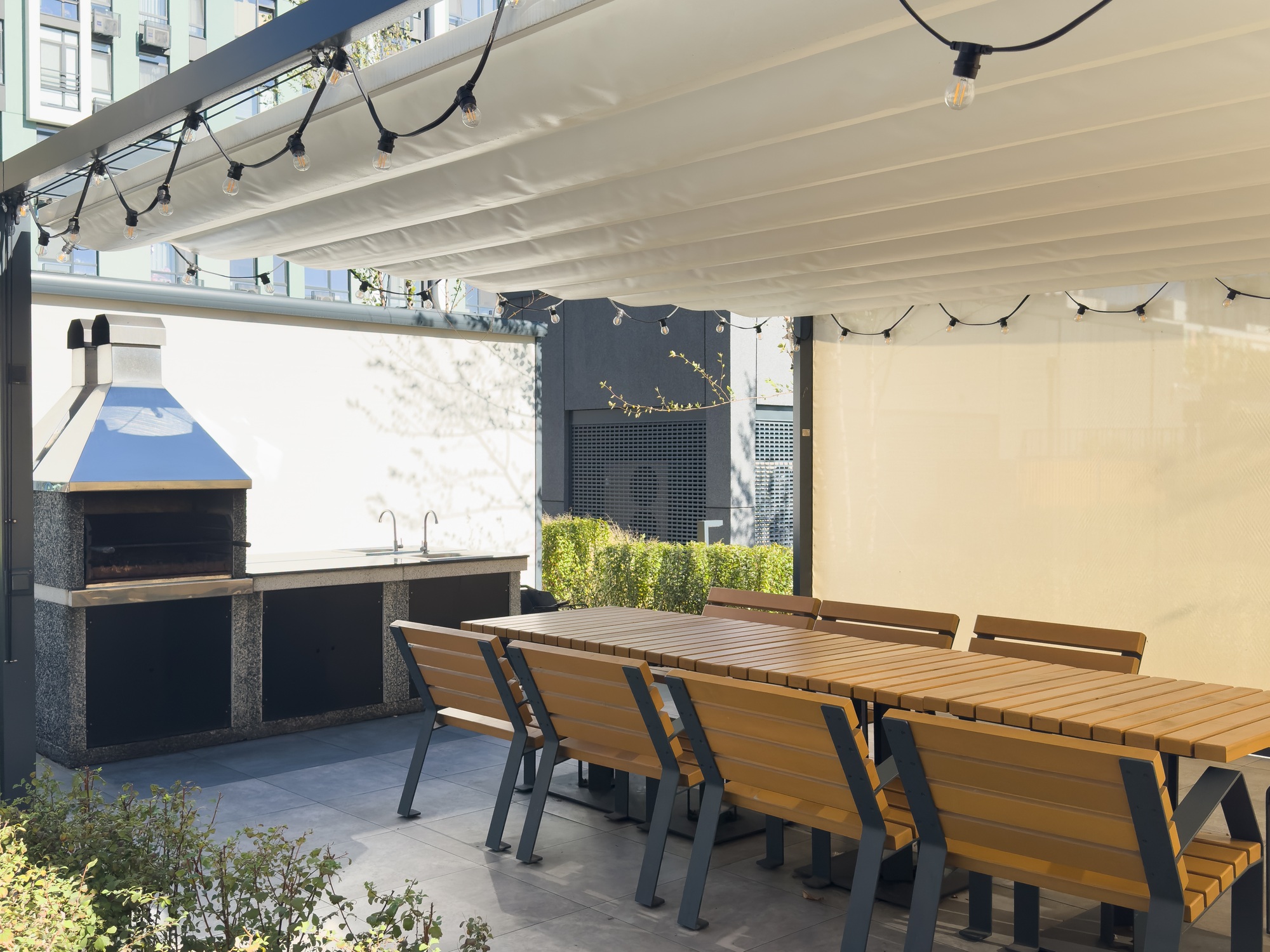 A spacious barbecue area with a canopy made from natural materials, enclosed. A patio with a table