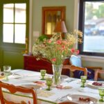 Elegant formal dining room table set for spring, featuring a crisp white tablecloth, floral centerpieces, fine china, and polished silverware, creating a welcoming atmosphere for family gatherings