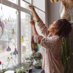 Woman holding handmade glass decoration in the form of heart standing in home decor studio