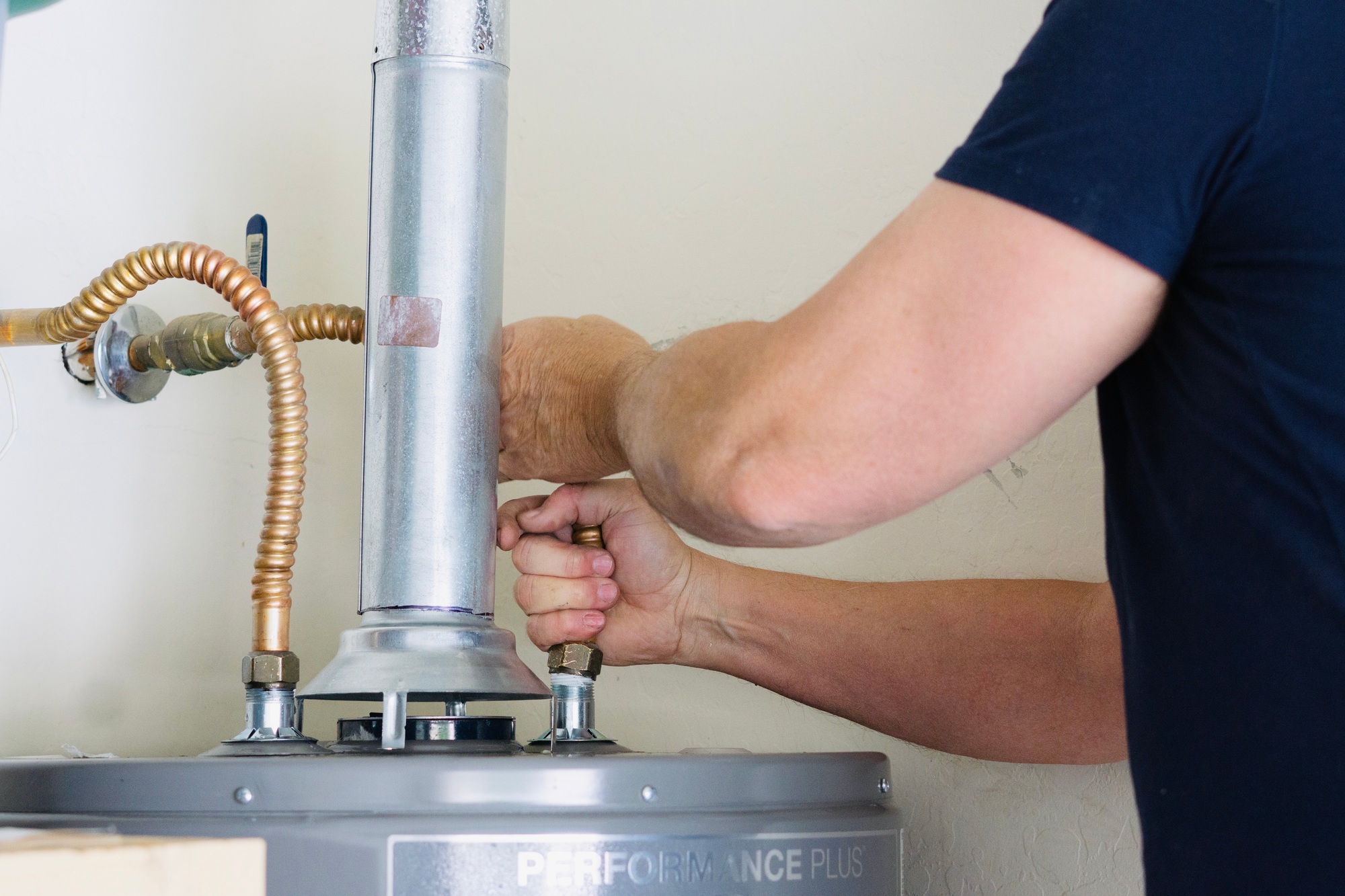 A Meraki technician tightening connections and making adjustments on a newly installed hot water heater, ensuring reliable home plumbing performance