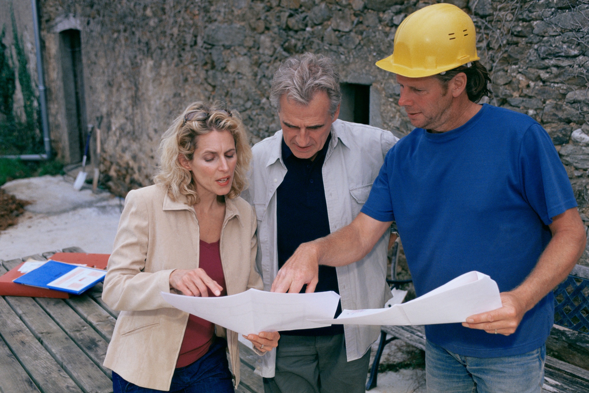 A couple and a Meraki builder reviewing detailed renovation plans together, planning a personalized home remodel with expert guidance