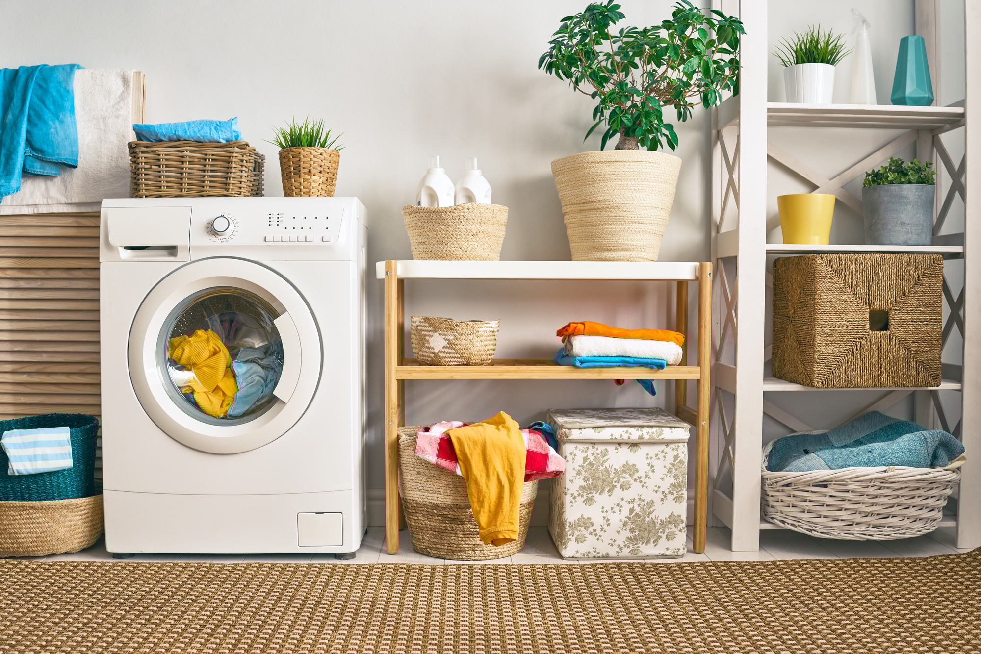Bright laundry room with a front-loading washing machine, storage cabinets, and a countertop for folding clothes