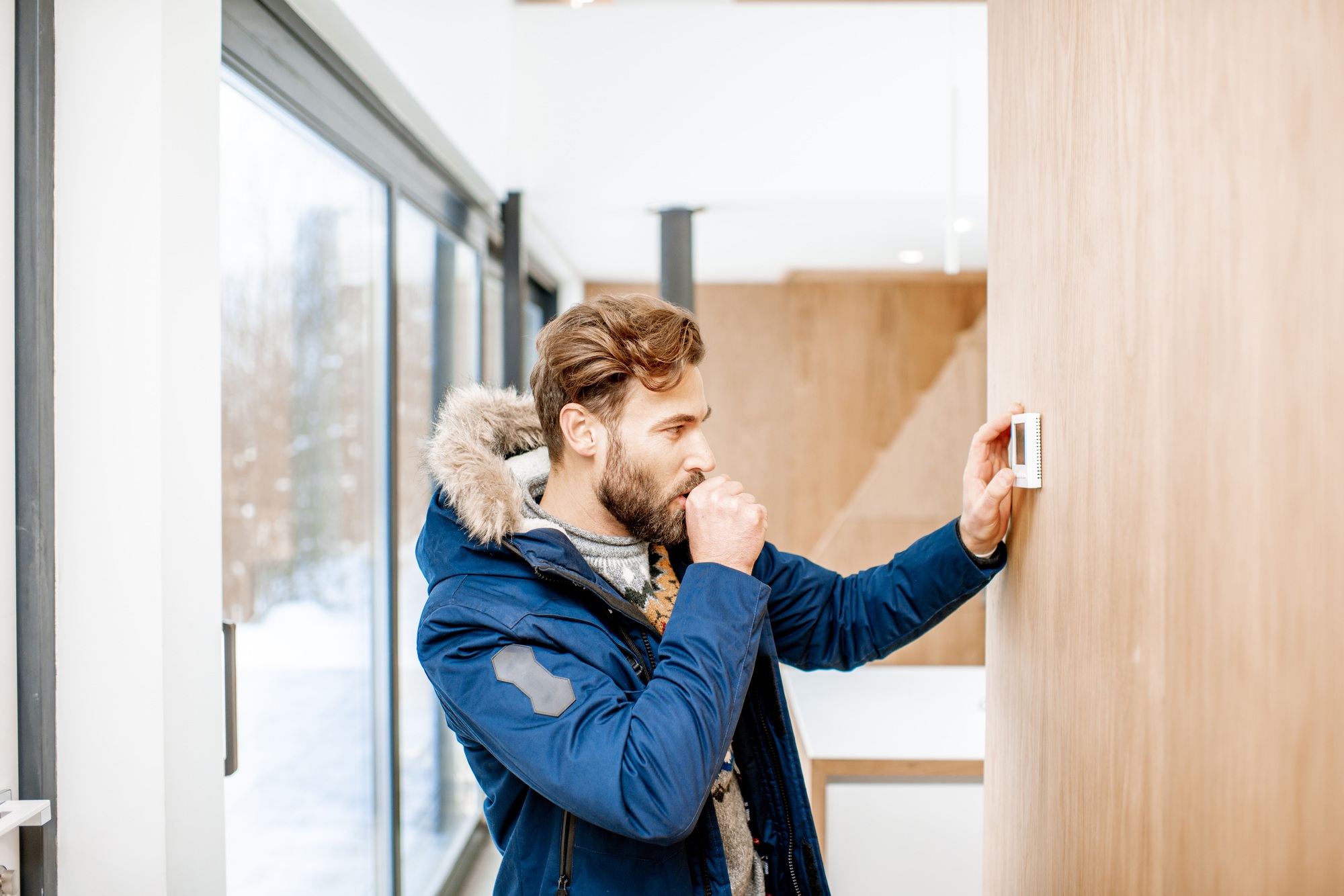 A homeowner adjusting the temperature on a smart thermostat installed by Meraki Builder, optimizing comfort and energy efficiency