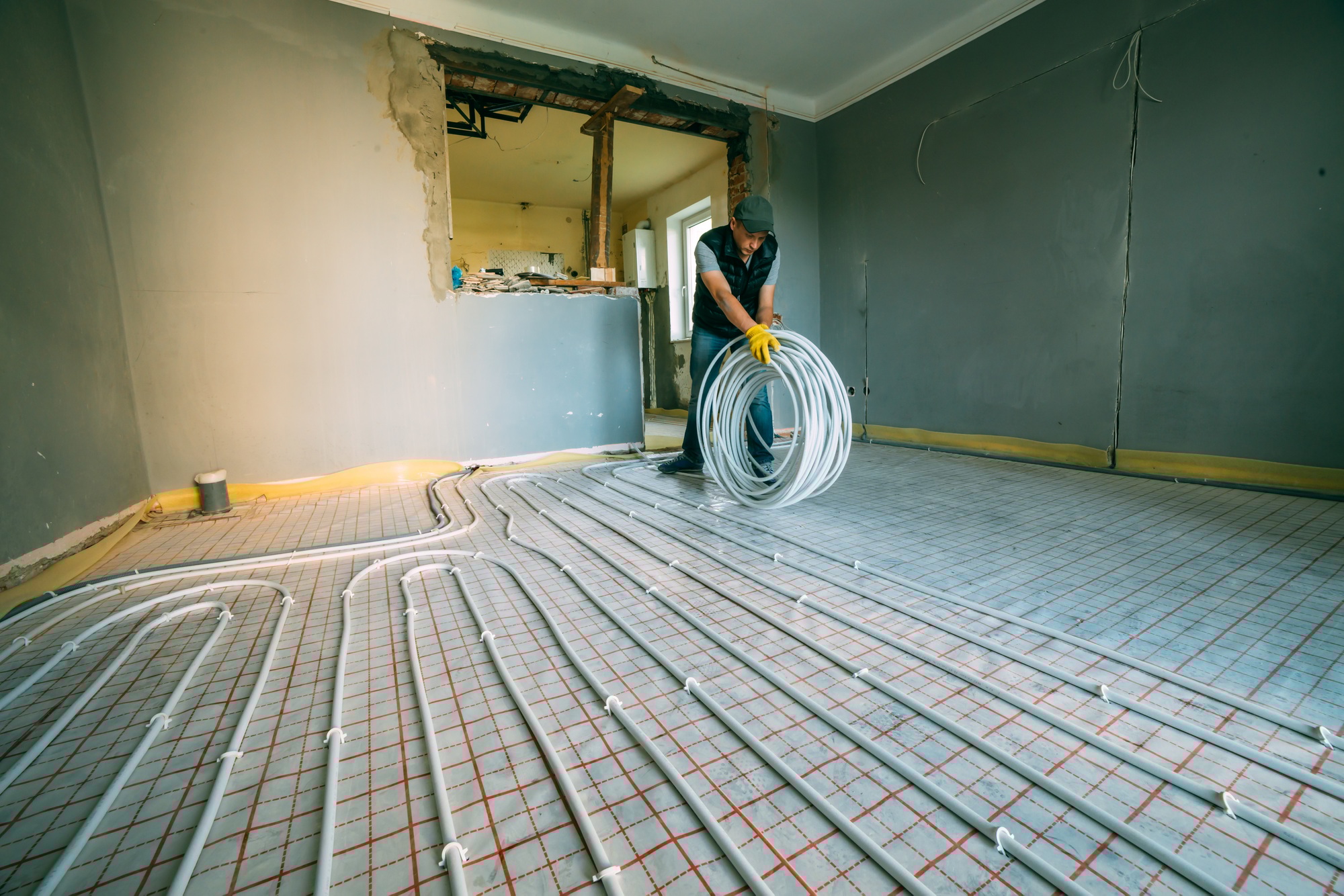 A skilled Meraki pipefitter installing an efficient radiant floor heating system, enhancing home comfort and energy performance