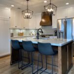 Charming small farmhouse kitchen remodeled by Meraki Builder, featuring white cabinets, granite countertops, and stylish pendant lighting
